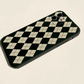 iPhone case with black colour based featuring white retro Checkerboard illustrations. Made from soft TPU polystyrene plastic material. Back angle view