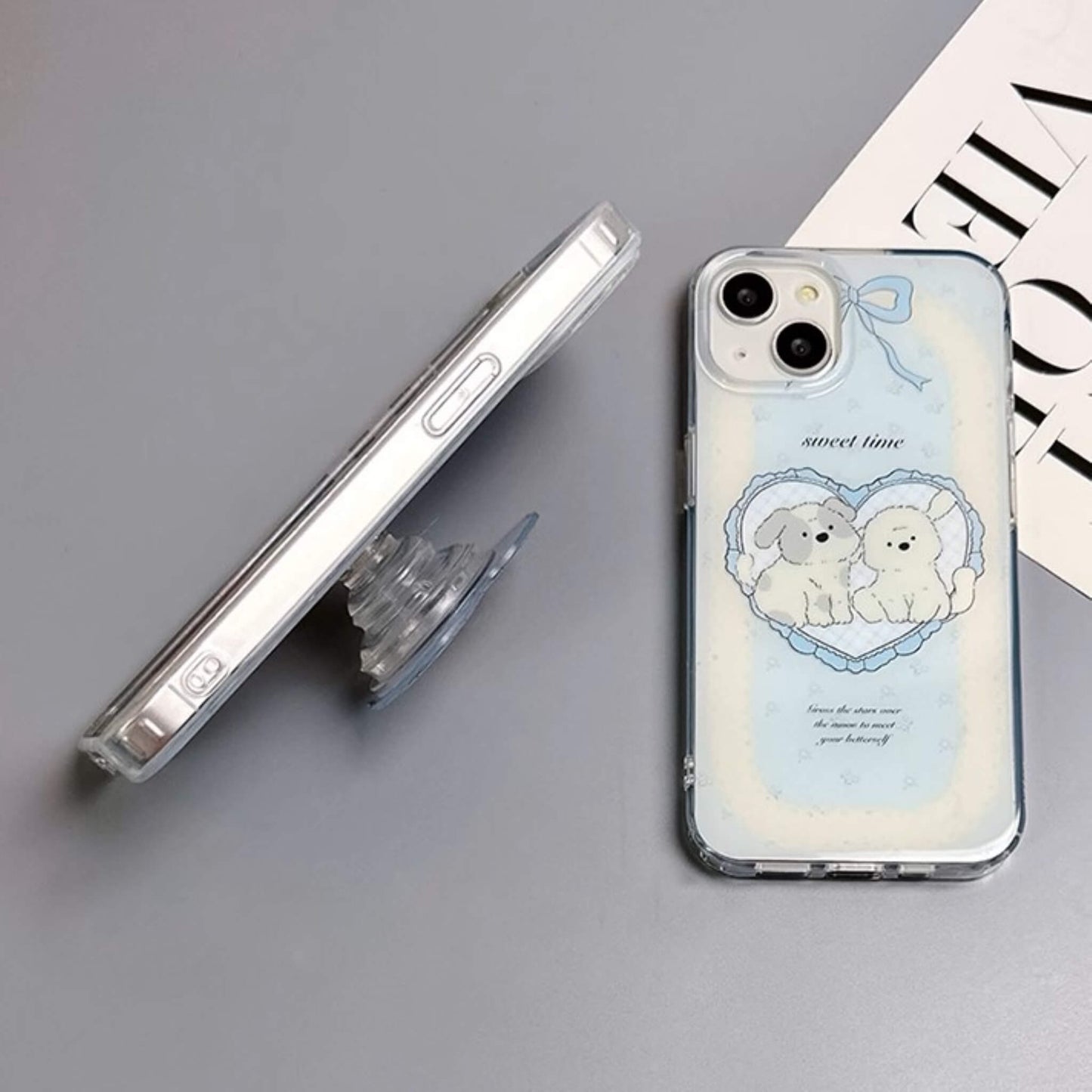 Charming MagSafe-compatible phone case displaying a heart with two cute puppies and 'sweet time' text, against a sky-blue background with soft clouds, next to a heart-shaped MagSafe popsocket with a matching design. Side View